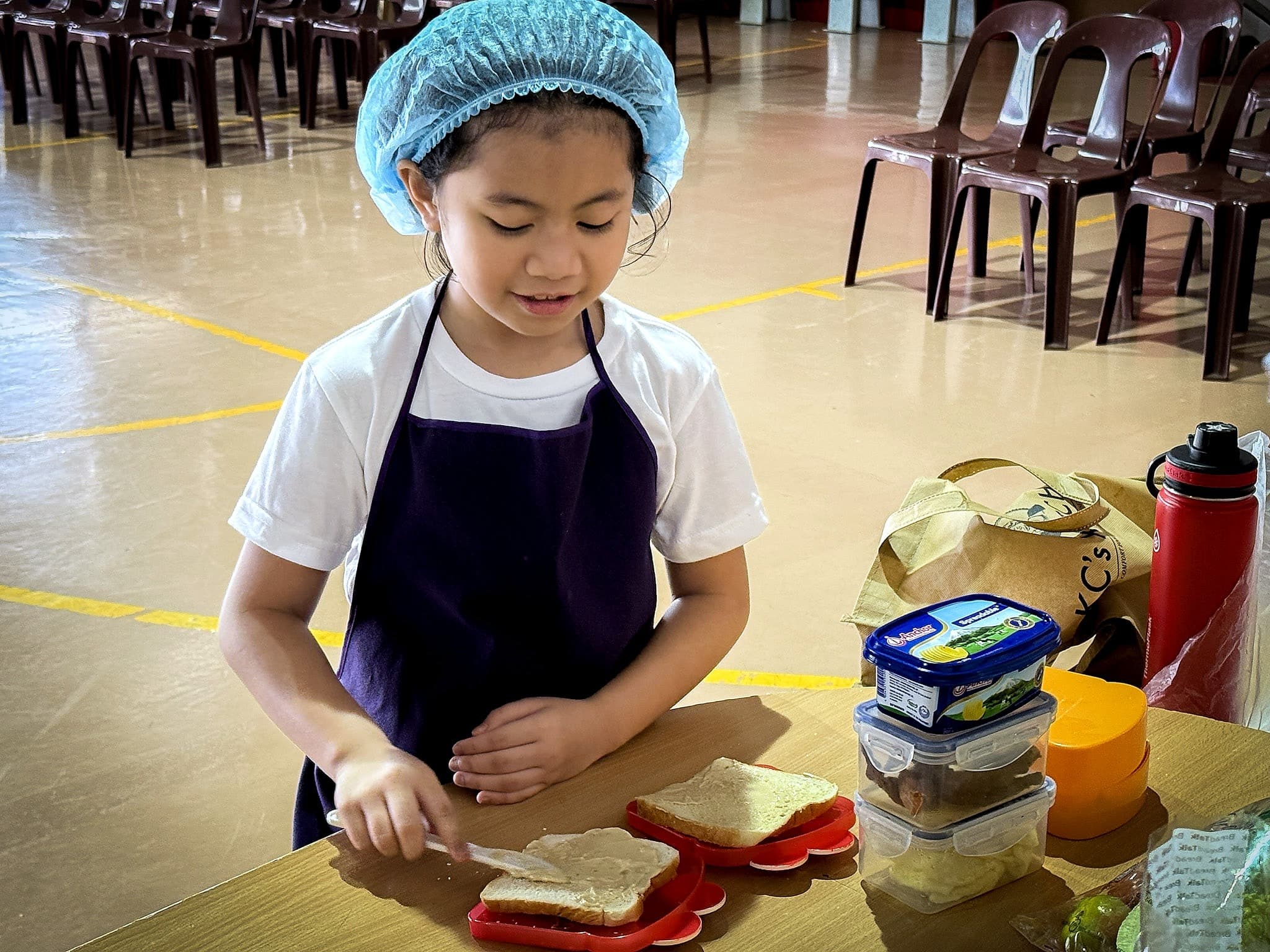 A young student preparing a sandwich independently during a practical activity at Leaders.