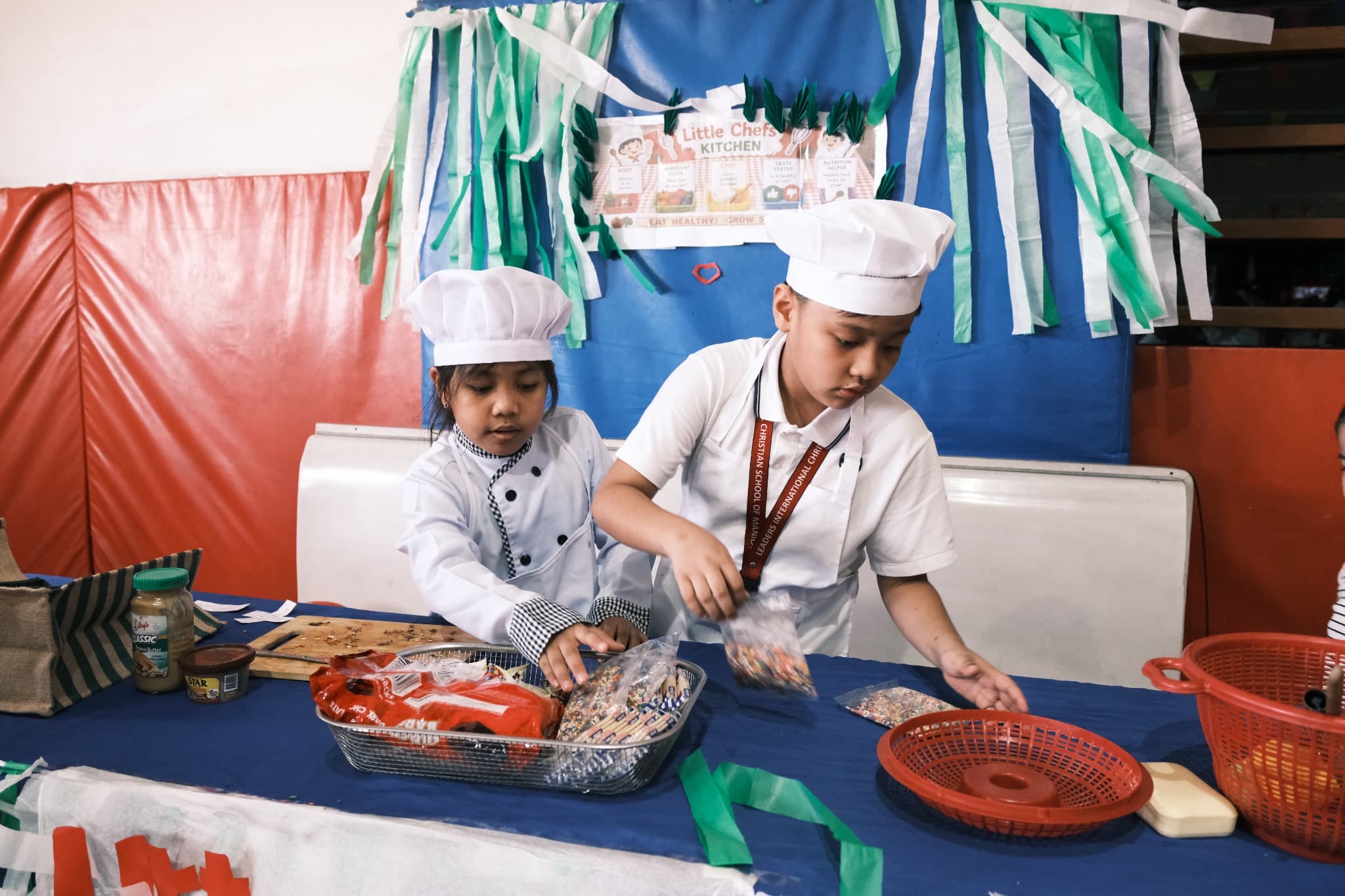 Two LICSM children taking part in a hands-on Little Chefs learning activity.