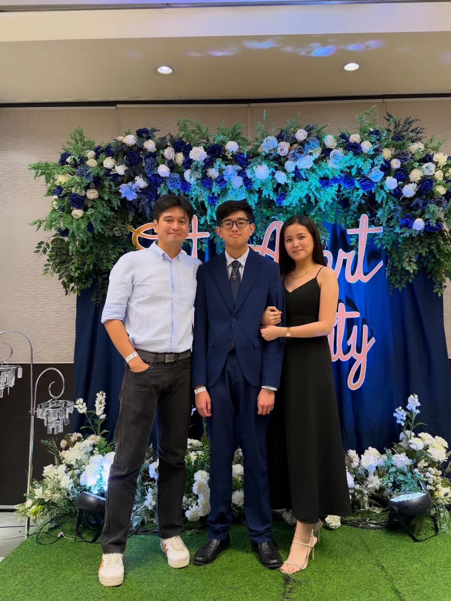 A family of three standing together at a formal celebration.