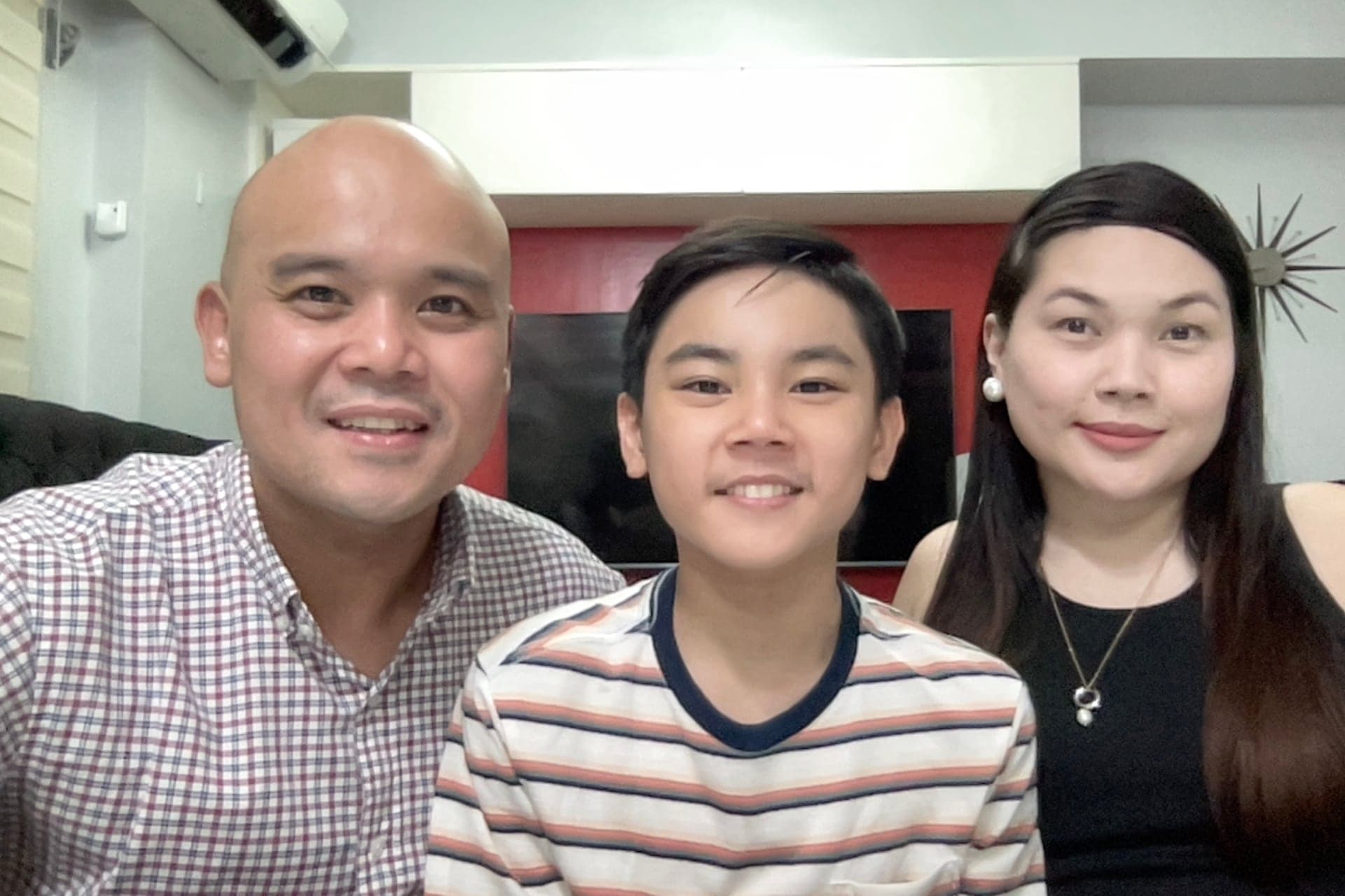 A family of three smiling together at home.