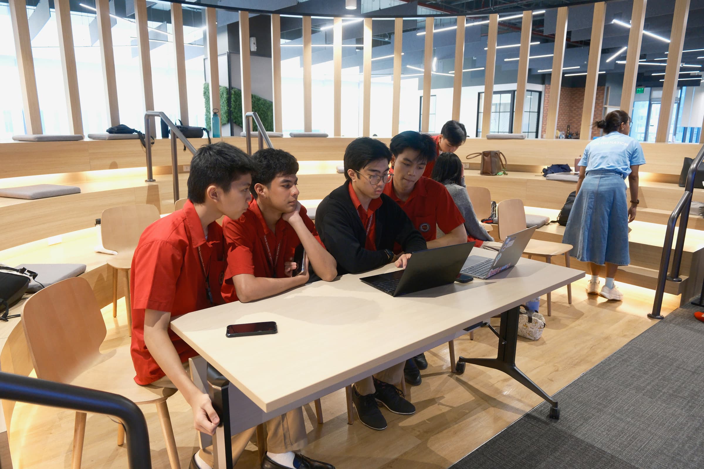 Junior high students working together around a laptop.