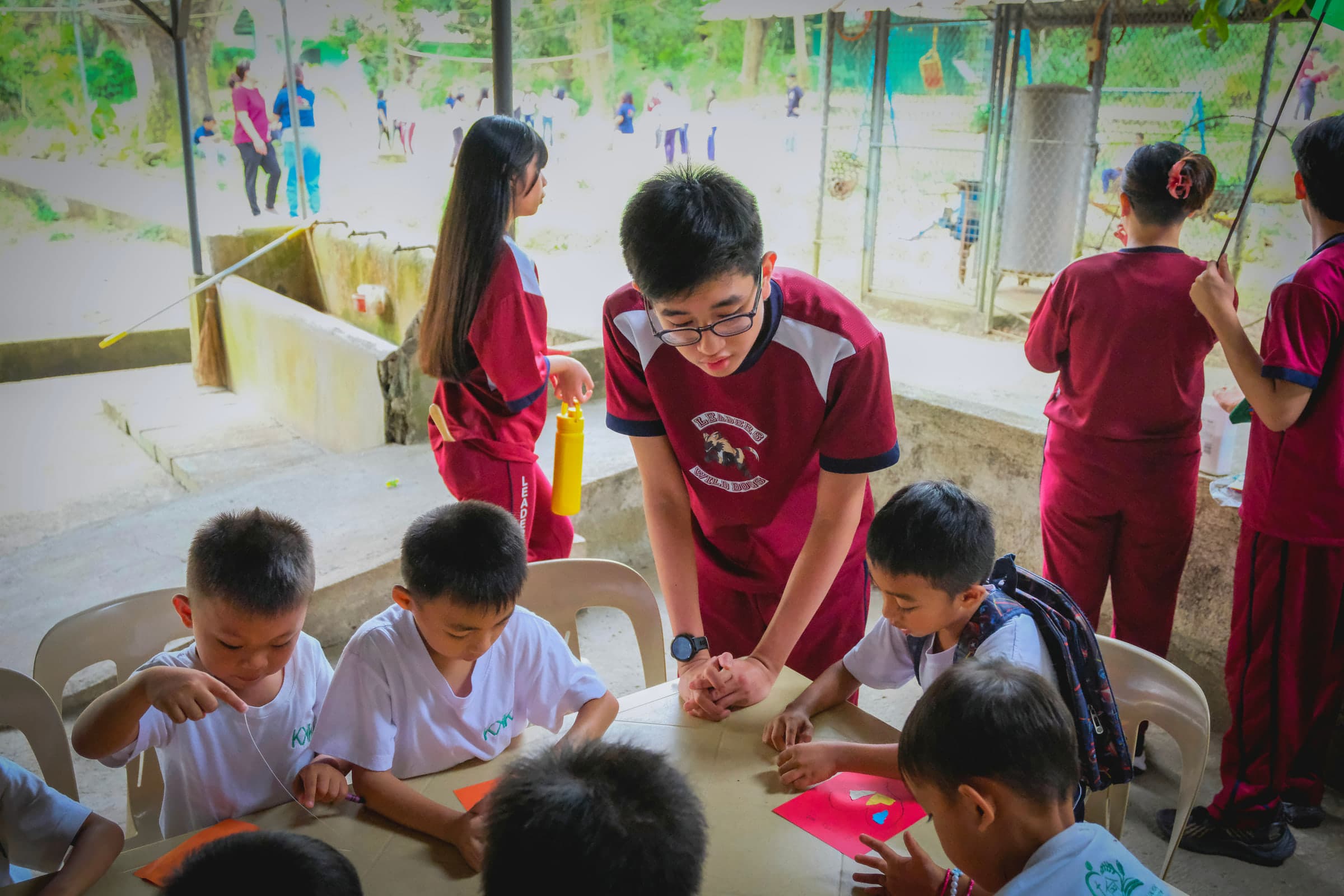 An older student at Leaders guiding younger students during a group activity.