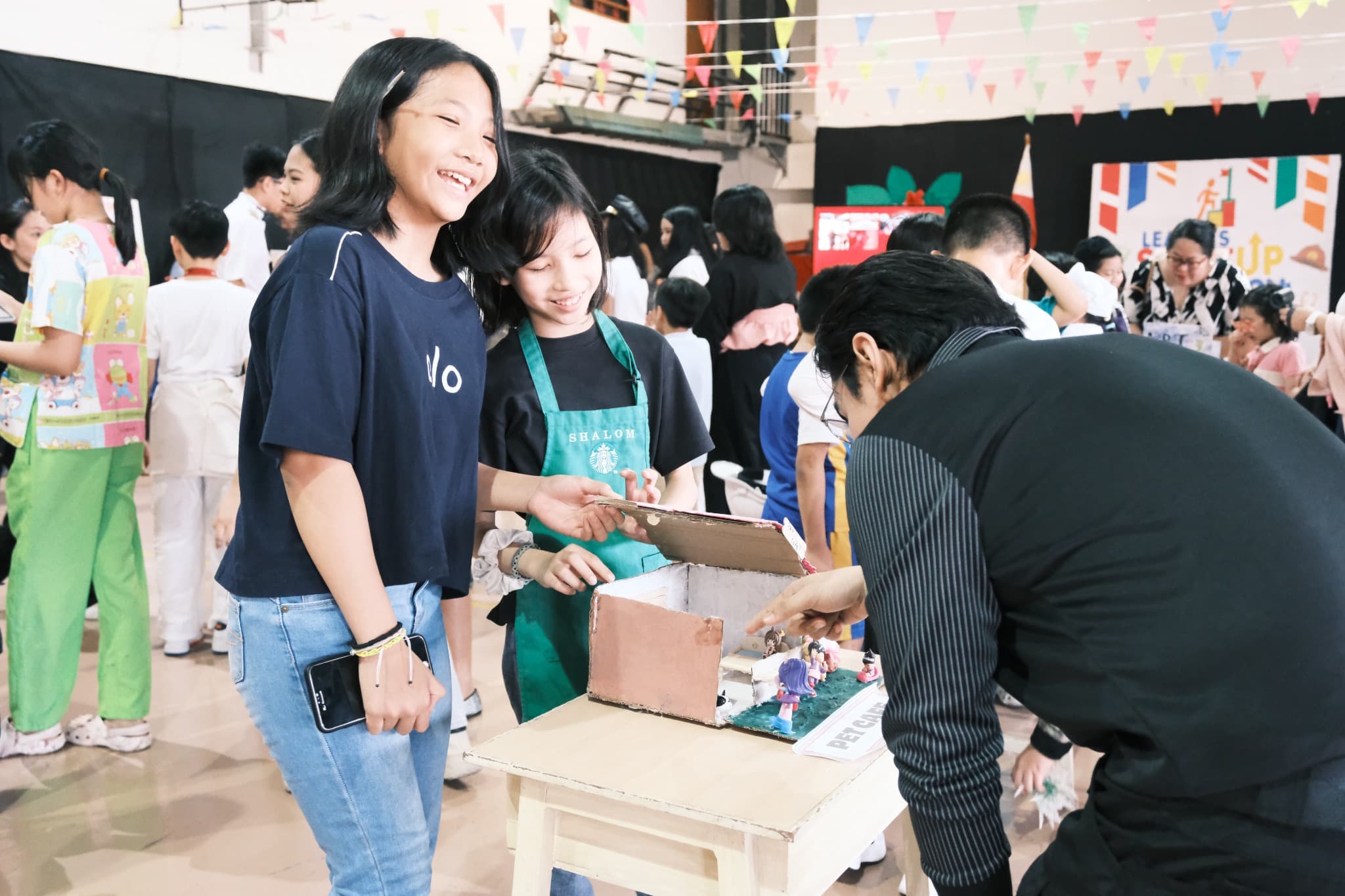 LICSM students sharing a creative project during a school activity.