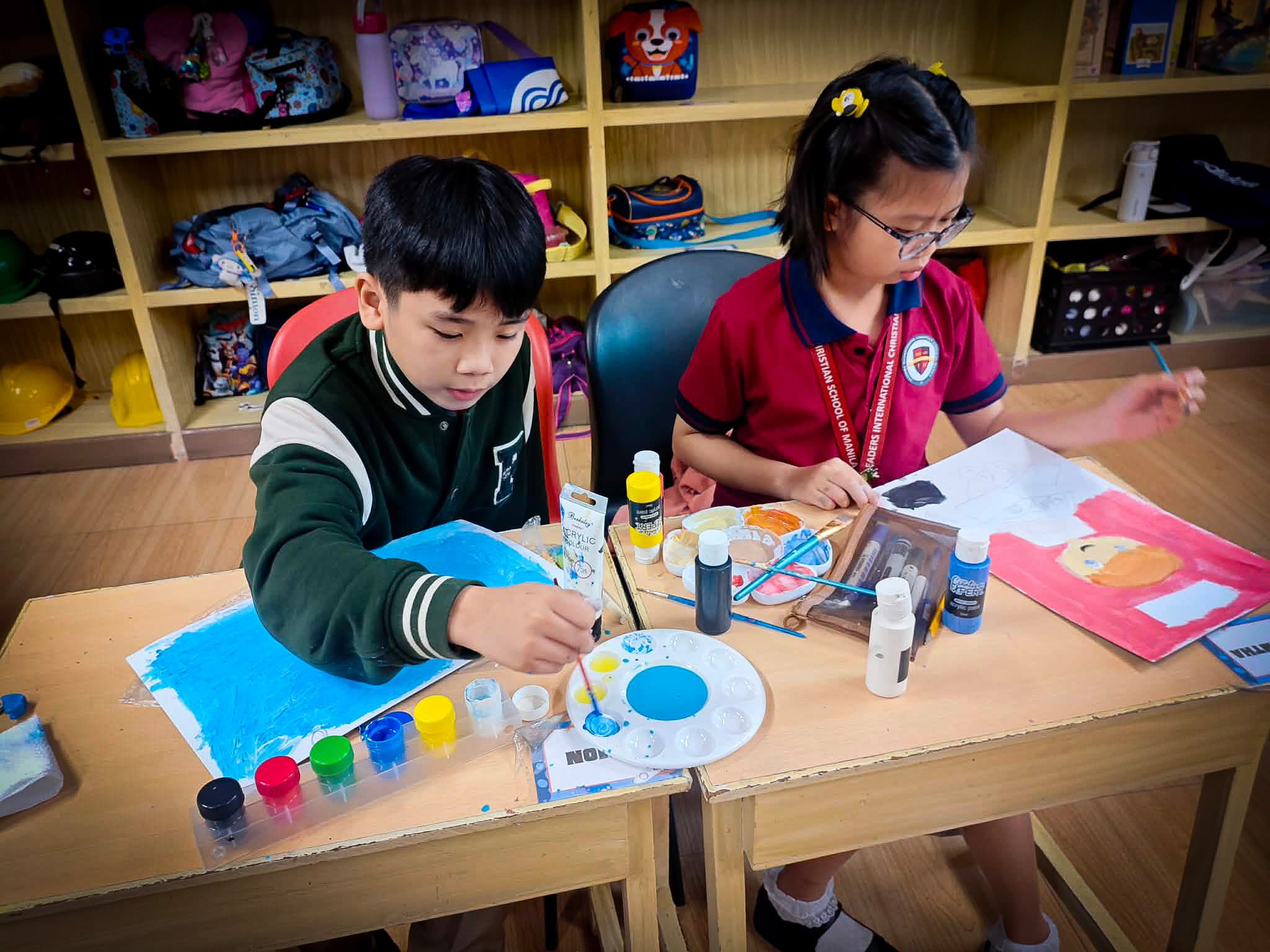 Elementary students painting together during an LICSM art class.