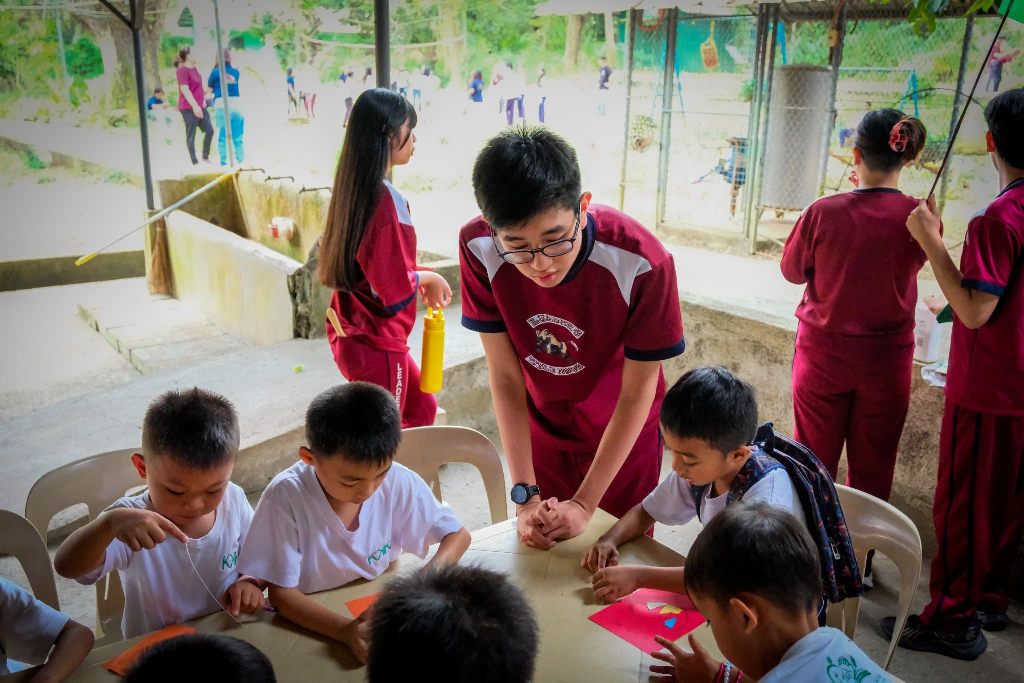 An older LICSM student guiding younger students during a group activity.